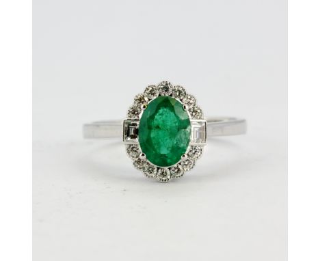 An 18ct white gold (stamped 750) ring set with an oval cut emerald and brilliant cut diamonds, (N.5).