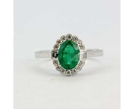 An 18ct white gold (stamped 750) ring set with an oval cut emerald and brilliant cut diamonds, (N.5).