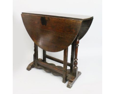 A MID 18TH CENTURY OAK DROP LEAF GATE LEG TABLE, with an oval shaped top, turned end supports united by a shaped stretcher. 3