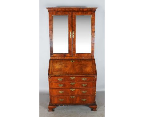 AN 18TH CENTURY WALNUT BUREAU BOOKCASE, the top with a pair of mirrored doors, with two brushing slides on a bureau base with