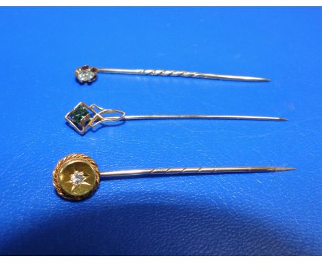 Two Edwardian yellow metal stick pins set diamonds; a similar set with green coloured stone