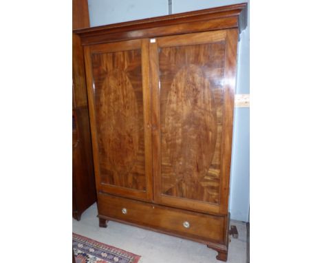 An Edwardian figured mahogany wardrobe with 2 oval panel crossbanded doors over drawer, on bracket feet
