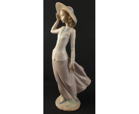 An attractively svelte LLADRO female figurine being blown by the wind. Handmade in delicately timeless pastel colours. No.:56