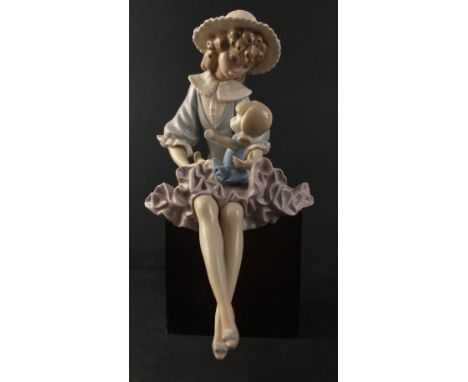 A beautiful LLADRO figurine of a young girl holding a doll in her lap sitting on a black plinth. Approx. 28cm in height. In e