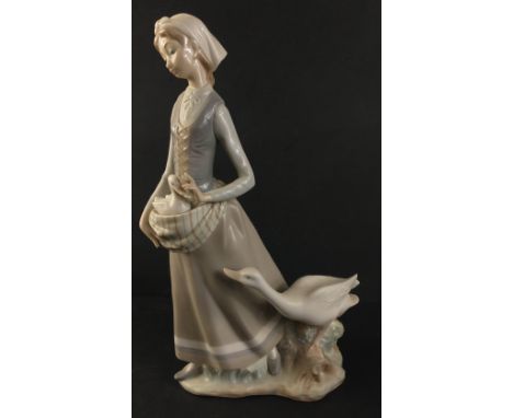 A LLADRO female figurine of a country girl nestling a gosling in her apron followed by a concerned mother goose. Handmade in 