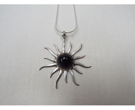 A modernist white metal and cabochon amethyst sun pendant on chain 