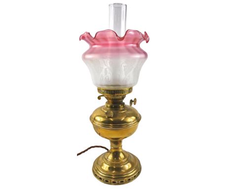 A brass oil lamp, the pink and white frosted shade decorated with flowers in Art Nouveau style, 50cm high.  WARNING! This lot
