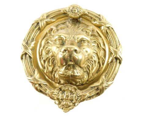 A large brass lion mask door knocker, with circular wreath decorated with flower heads, ribbons, etc., 22cm diameter. 