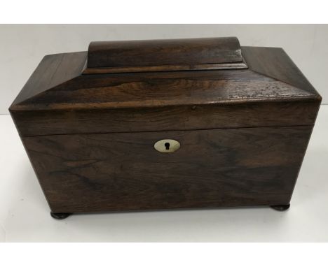 A 19th Century rosewood tea caddy of sarcophagus shaped form, the hinged lidded top opening to reveal a fitted interior and c