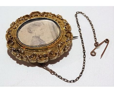 Victorian gold sea scroll embossed and chased and engraved oval brooch with glass panel containing a photograph portrait of a