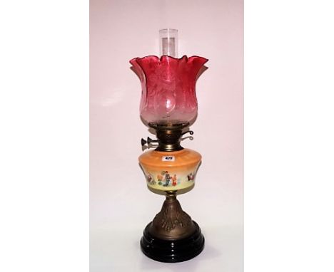 Brass and porcelain oil lamp with blush cranberry glass flower etched shade and on black pottery socle, height 52cm.