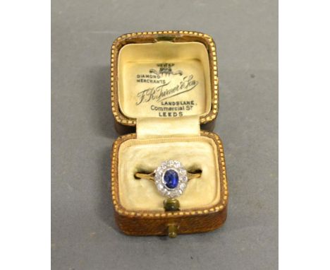 A Yellow Metal Sapphire and Diamond Cluster Ring with a central oval sapphire surrounded by diamonds within a pierced setting