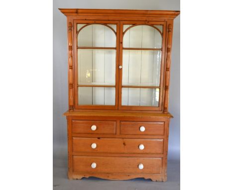 A 19th Century Pine Bookcase, the molded cornice above two arch glazed doors, enclosing shelves, the lower section with two s