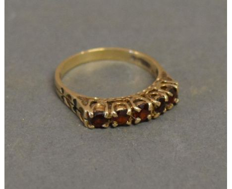 A 9ct. Yellow Gold Garnet Set Ring with five garnets within a pierced setting 