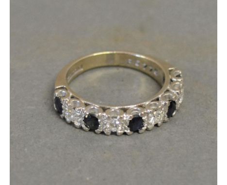 An 18ct. White Gold Sapphire and Diamond Half Eternity Ring, set with four diamonds and five sapphires within a pierced setti