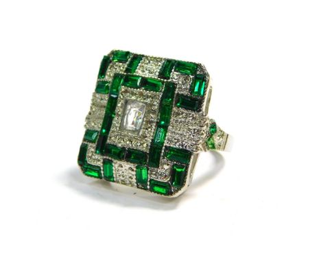 A modern Art Deco style dress ring, set with clear and green coloured paste, on a silver coloured band, size x.