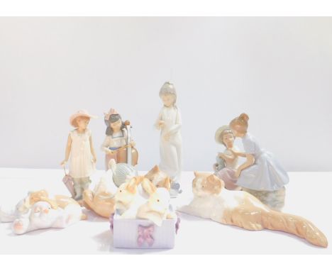 A group of Nao porcelain figures, including two girls with a doll, girl cello player, two puppies, cat, and a box of rabbits.