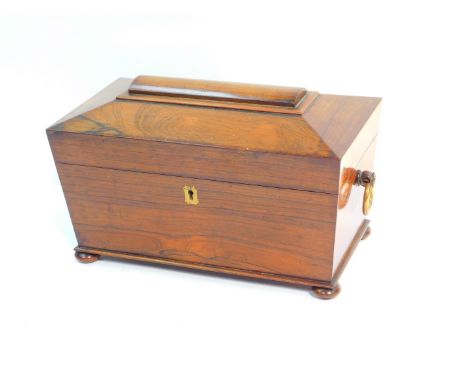 A Regency rosewood tea caddy of sarcophagus form, with ring handles, the hinged lid opening to reveal three recesses, raised 