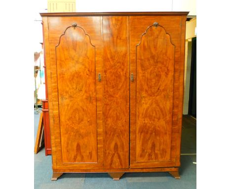 An early 20thC walnut and mahogany compactum wardrobe, the outswept pediment over two doors, flanking a centre panel opening 
