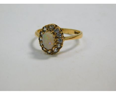 An 18ct gold and opal ring, set in a surround of clear brilliant cut stones, possibly white sapphires, size N, 2.4g.