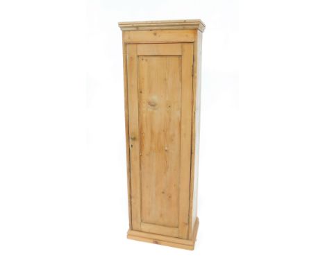 A slender pine cupboard, with moulded top, enclosed by a single panel door, and fitted with three shelves within, on a plinth