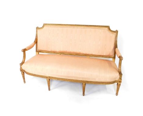 An early 19thC French style giltwood sofa, upholstered in over stuffed pink moire silk, with acanthus scroll open arms and ra