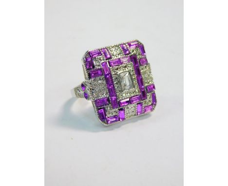 A modern Art Deco style dress ring, set with clear and lilac coloured paste, on a silver coloured band, size Z.