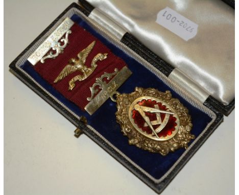 A rolled gold Masonic medal, with compass and set square to obverse, within thistle decorated border, the red ribbon with Rom