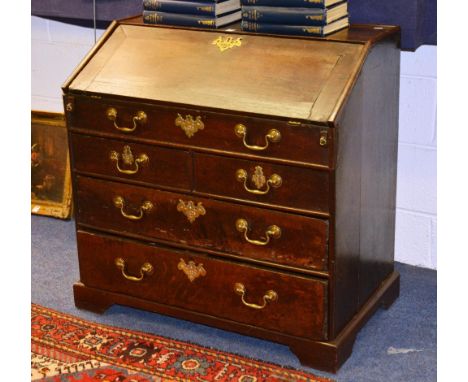A Georgian oak writing bureau, with hinged writing flap enclosing fitted drawers and pigeon holes, above graduated drawers ra