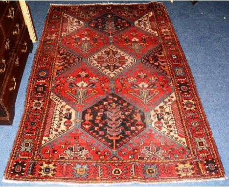 A vintage Persian Bahhtiari carpet, the floral and dog tooth diamond design over red ground and floral border, 203 x 139cm