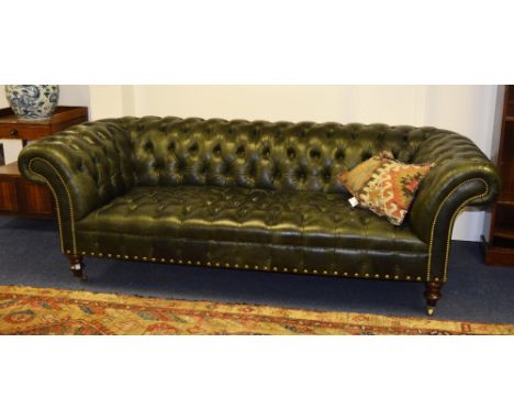 A green leather Chesterfield button back settee, labelled Greengate to underside, in the club style, raised on screw on turne