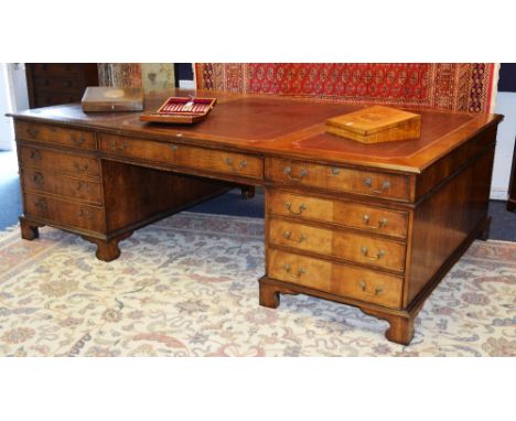 A large mahogany partners desk, the top with tooled red leather inset, above three drawers raised on two pedestal bases with 