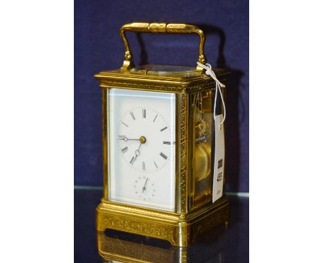 A brass embossed carriage clock, with carry handle and glazed top, the white dial with Roman numerals and subsidiary seconds 