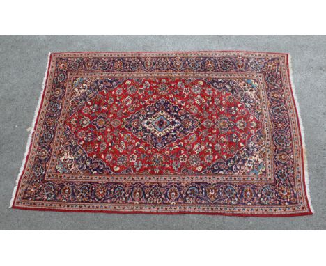 Modern Kashan carpet with all-over floral decoration on a red ground with multiple borders, 300 x 200cm approximately