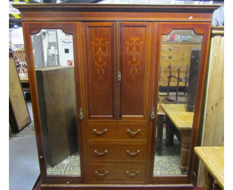 An inlaid Edwardian mahogany triple compactum wardrobe, the central section fitted with three long drawers beneath a linen cu