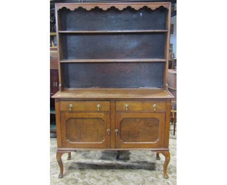 An Edwardian stained oak dresser, the base enclosed by a pair of rectangular moulded panelled doors and two frieze drawers, o