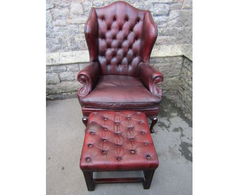 A reproduction Georgian style brown leather upholstered wing armchair with shaped outline, button back and studded detail, lo