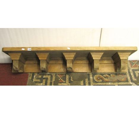 A substantial stripped pine shelf with moulded and shaped supports, 127 cm long x 34 cm wide x 20 cm deep