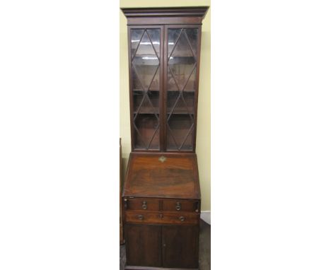 A small Regency mahogany bureau bookcase, the fall flap enclosing a simply fitted interior over an arrangement of drawers and