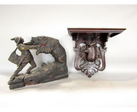 Black forest carving of a bear attacking a man, 38cm long; together with a further black forest wall bracket with stag head d