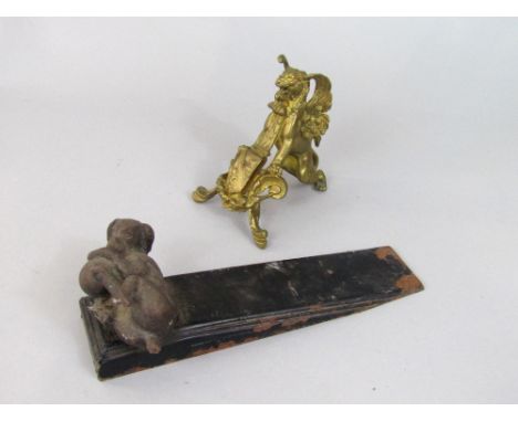 Novelty cast metal door wedge with cast bronze playful dog mount, together with a further ormolu mount of a winged lion (2)