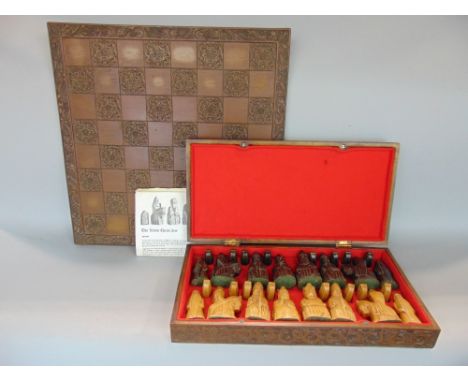 'The Lewis Chess Set' comprising a hardwood box fitted with various carved figural chess pieces and a further games board car