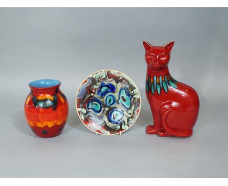 A collection of Poole Pottery wares comprising a red glazed model of a seated cat, 29.5cm tall a vase with abstract detail, 1