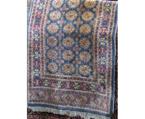 Persian full pile Bokhara type rug with typical geometric cream medallions upon a light blue ground, 210 x 125cm