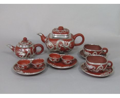 A collection of oriental terracotta teawares with white metal overlay in the form of dragons, comprising teapot of square sha
