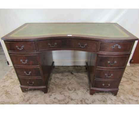 A reproduction Georgian style kneehole twin pedestal writing desk with green leather inset panelled top over a serpentine fri