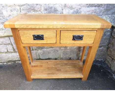 A contemporary light oak sideboard fitted with two frieze drawers, raised on square cut supports, united by an under tier/pot