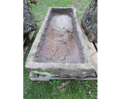 A shallow rough hewn natural stone trough of rectangular form, approx 115cm long x 50cm wide x 20cm high