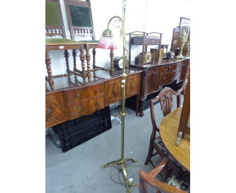 AN EARLY TWENTIETH CENTURY BRASS STANDARD LAMP WITH SCROLL HANDLE OVER SHAPED ARM AND CRANBERRY CRISS-CROSS PATTERN GLASS SHA