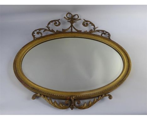 An Antique Oval Gilt Wood Mirror, bevelled glass, with bow and foliate decoration to top, approx 70 x 48 cms with frame.&nbsp